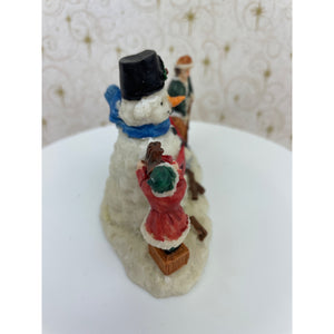 Snowman Figurine - Children Building a Snowman Holding a Merry Christmas Banner